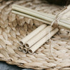 two bunches of bamboo straws both tied together with twine resting on a woven place mat