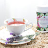 a white tea cup filled with pink tea on a saucer along with a few sprigs of lavender