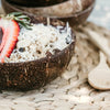 close up of a low-set coconut bowl filled with an acai smoothie topped with coconut, granola and a strawberry
