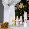four Mayella skincare products standing on white tissue paper with a white bag and christmas tree in the background