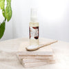 bottle of olivane repair serum spice infusion on a stack of four stone tiles next to a ceramic spoon
