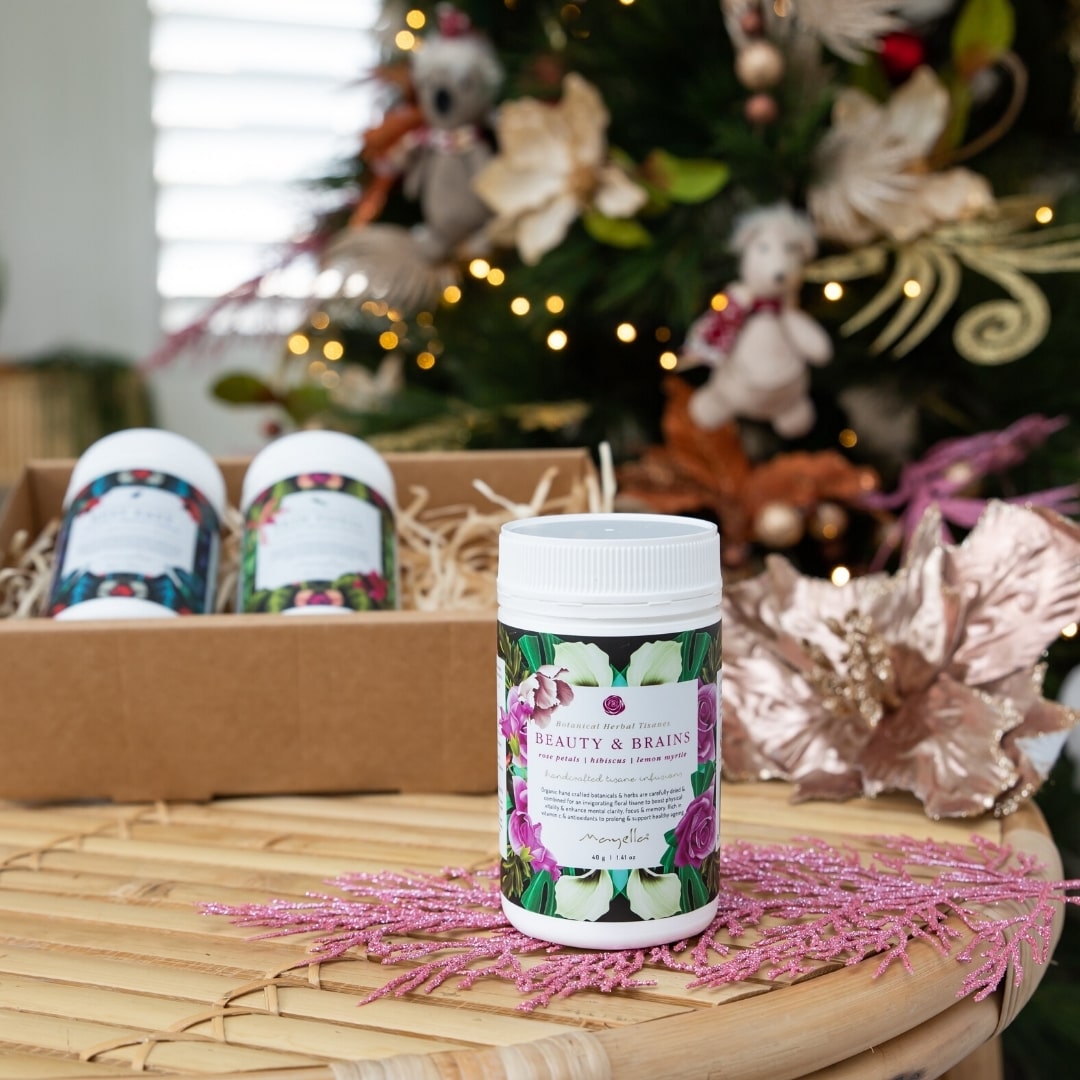 two organic teas in a cardboard gift box with one standing on a table. There is a christmas tree in the background