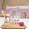three mayella repair serums on a timber tray on a boho styled bed with a pink rose and a small flower vase next to them