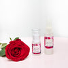 two bottles of olivane repair serum rose infusion in 15ml and 30 ml sizes on a light pink table next to a big red rose