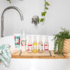 six mayella products in this pregnancy skin set on a timber bath caddy sitting on a white bath tub next to a flax pot with a small green plant
