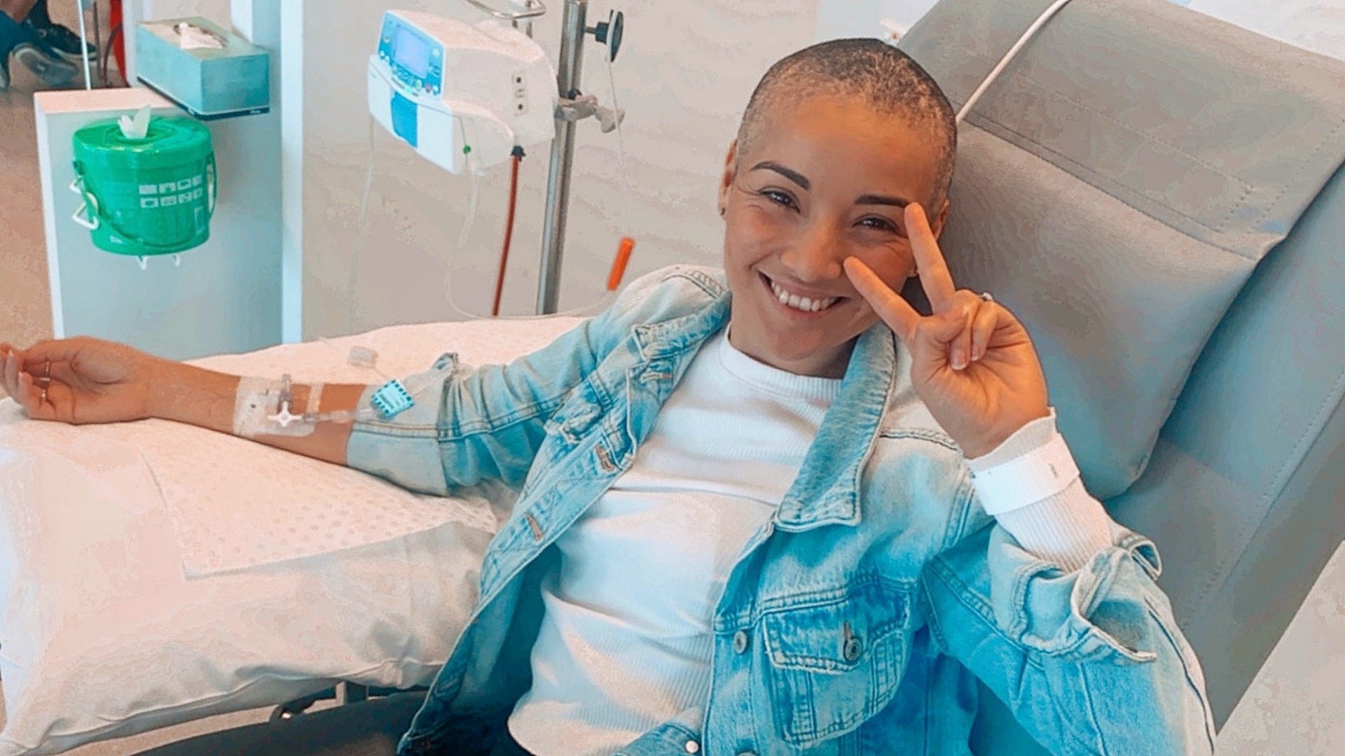 Lorena smiling and giving peace sign while receiving chemotherapy