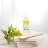 bottle of AHA exfoliating serum in 30 ml size on a file of three stone coasters next to a ceramic spoon and a small bunch of yellow and green foliage