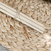 bunch of five bamboo straws and a straw cleaning brush tied together with twine and sitting on a woven place mat