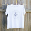 white t-shirt hanging against a timber fence, the design on the shirt is a silver leaf with text circling it that reads you gotta nourish to flourish