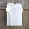 a creme-coloured t-shirt hanging against a timber fence, the design on the shirt is a small gold leaf with gold text underneath that reads positive mind, positive vibes, positive life