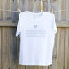 a white t-shirt hanging against a timber fence, the design on the shirt is a small silver leaf with silver text underneath that reads positive mind, positive vibes, positive life