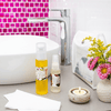 bottle of cleansing serum and olivane repair serum spice infusion on a grey bathroom vanity next to a white sink with bright pink tiles on the back wall