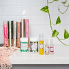 five mayella skincare products that make up this pack on a light stone kitchen bench top with six colourful cook books in a timber stand in the background
